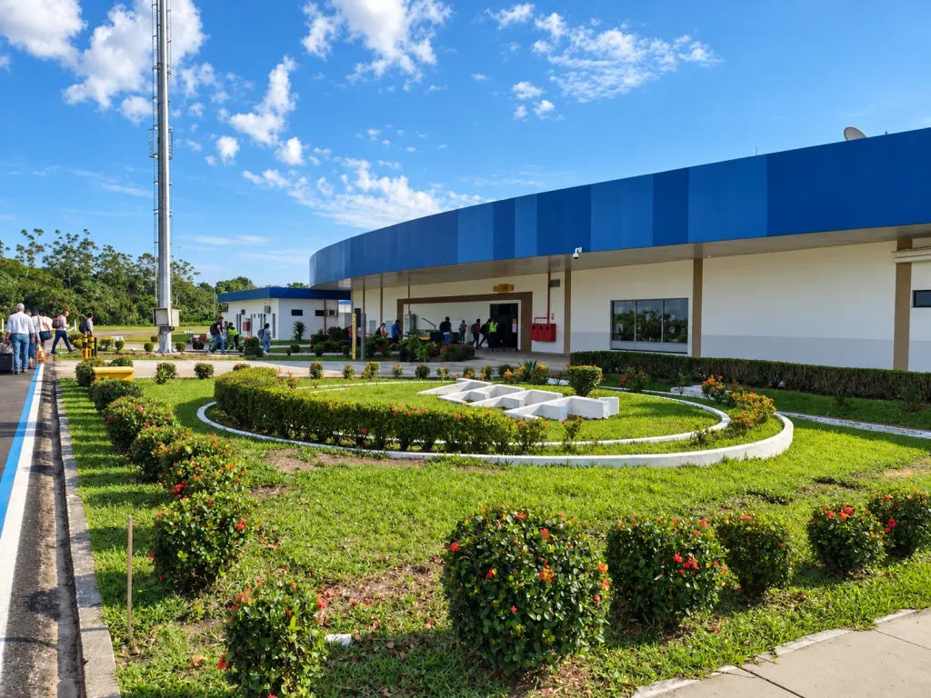 Imagem colorida do terminal de passageiros do Aeroporto Regional de Tefé, com jardim e mastro em frente
