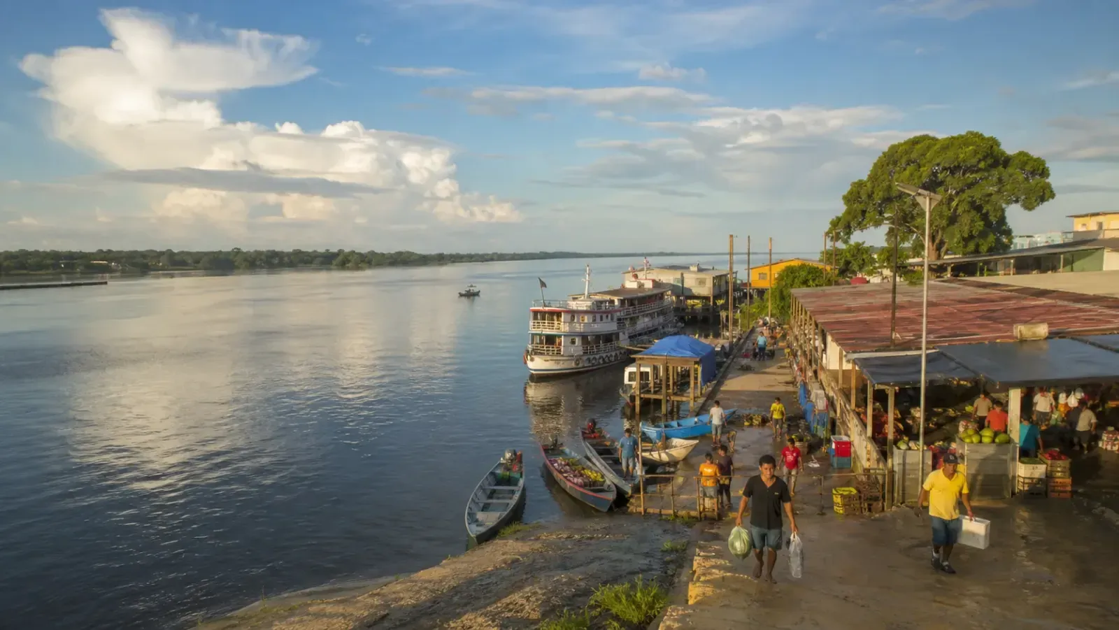 Orla amazônica com embarcação regional, comércio e moradores em Tefé